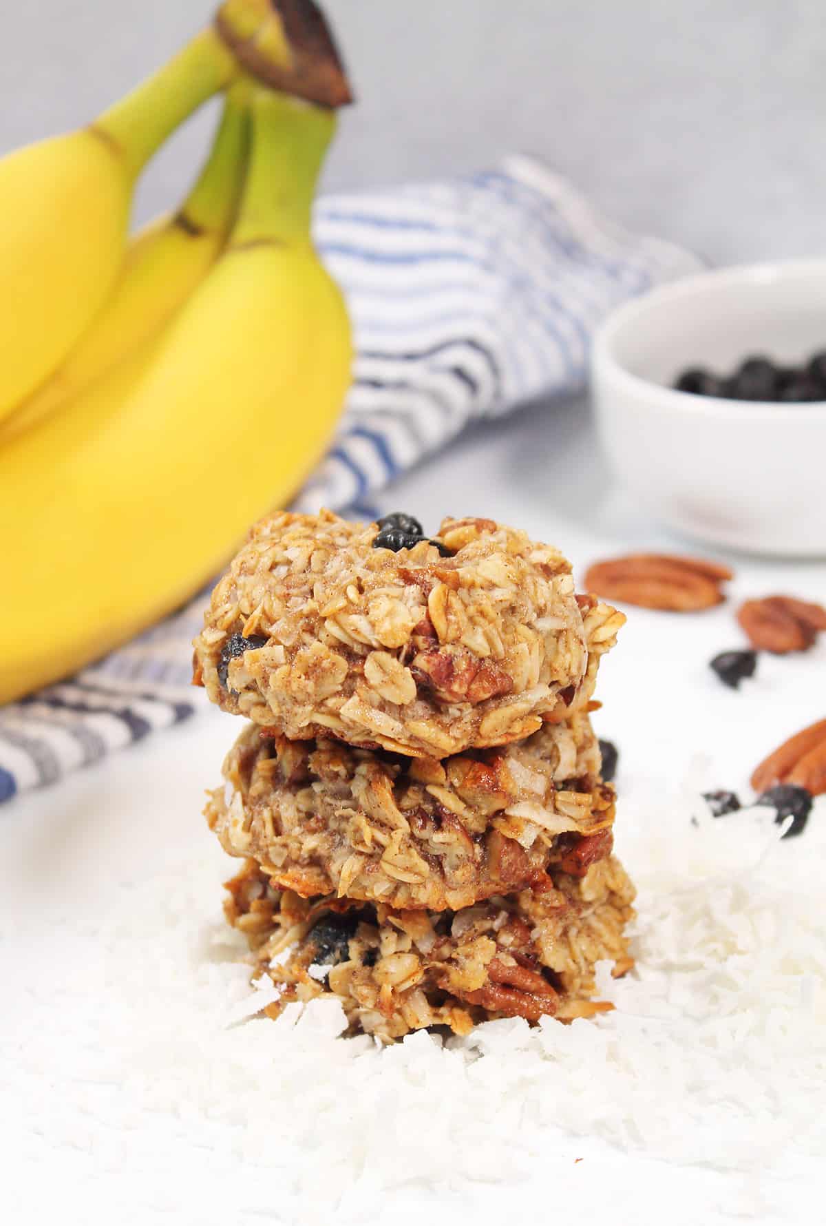 Stack of banana breakfast cookies with bananas and coconut.