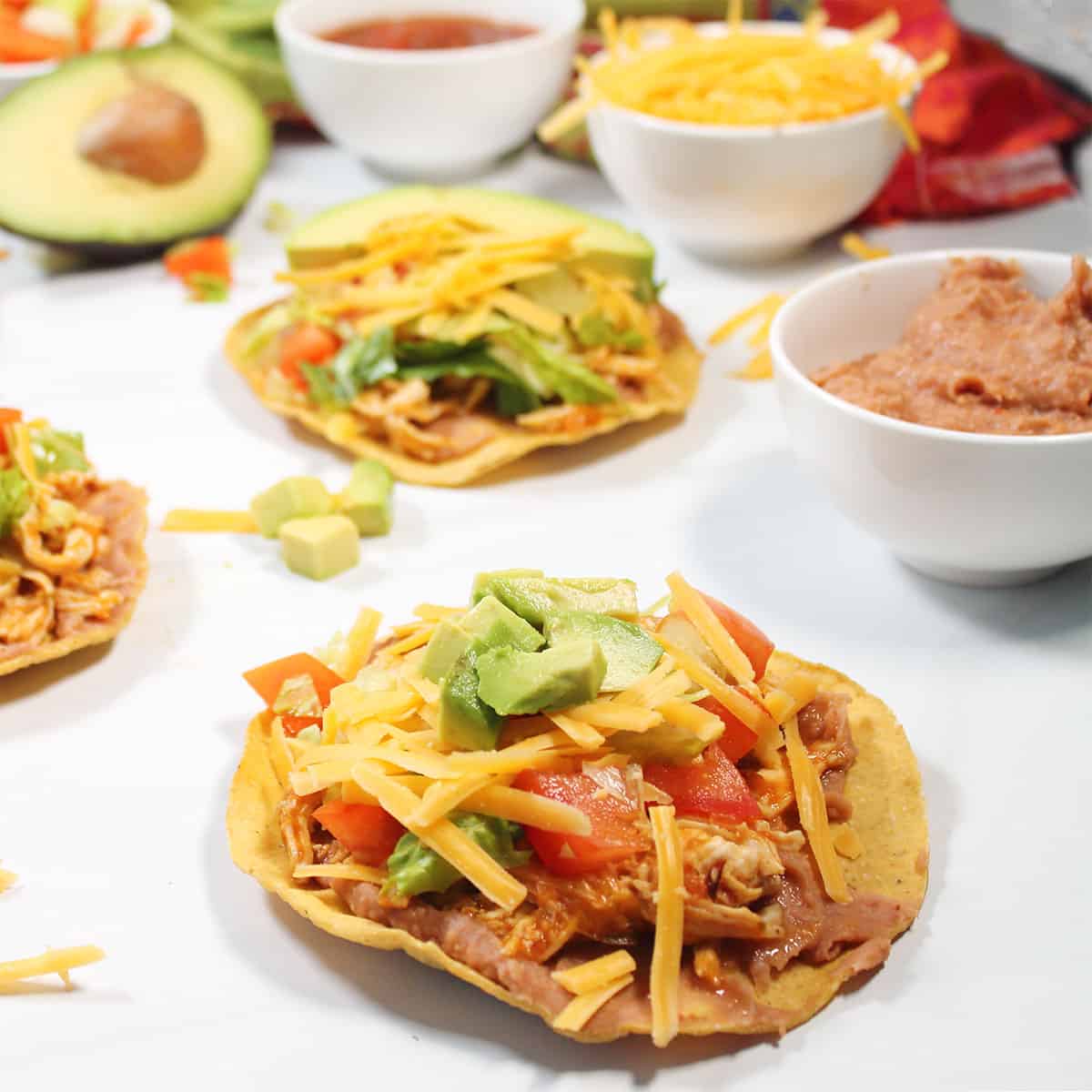Loaded up Chicken Tinga Tostadas on white table.