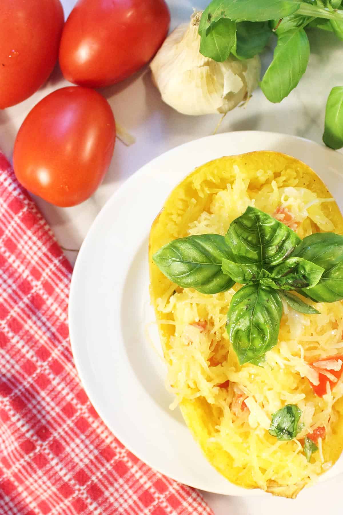 Overhead of baked stuffed spaghetti squash boat with tomatoes, garlic and basil.