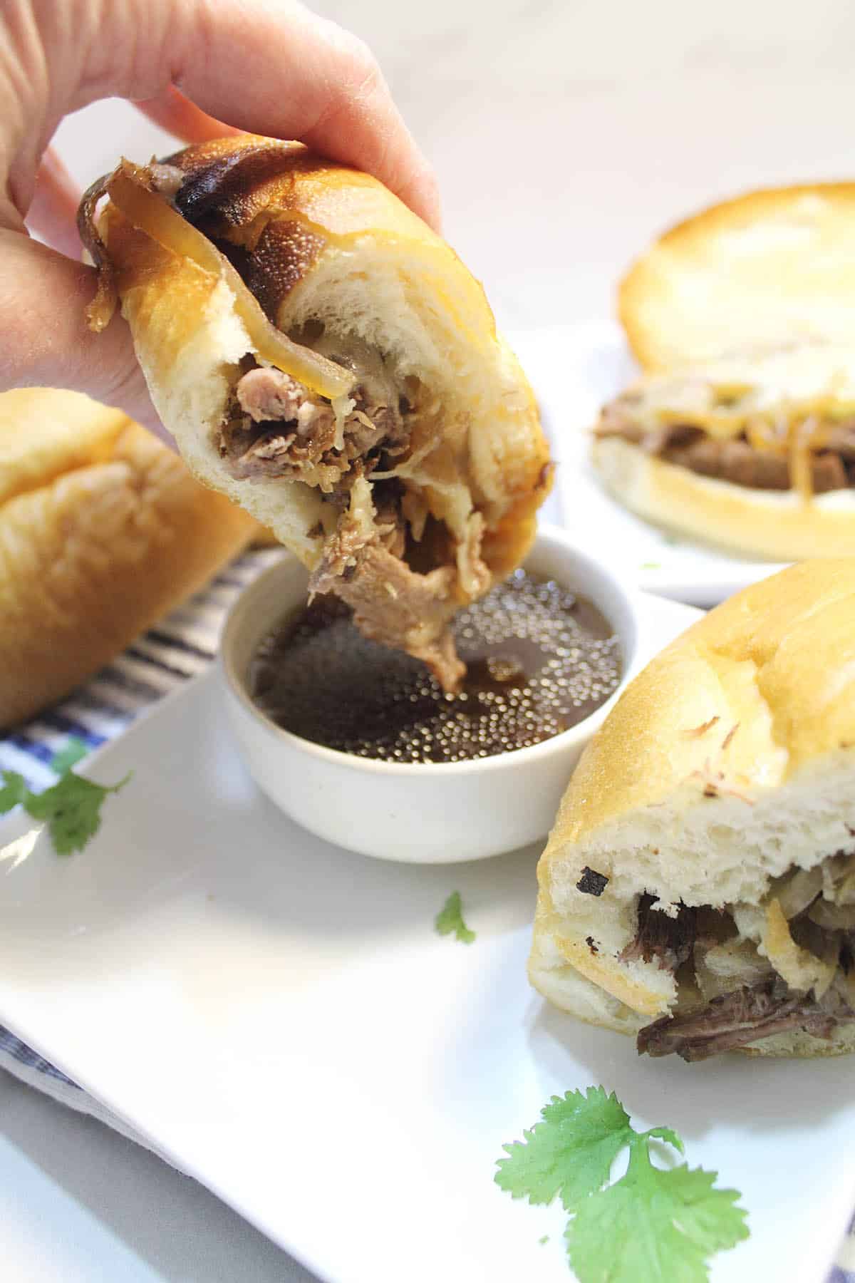 Dipping sandwich half in au jus.