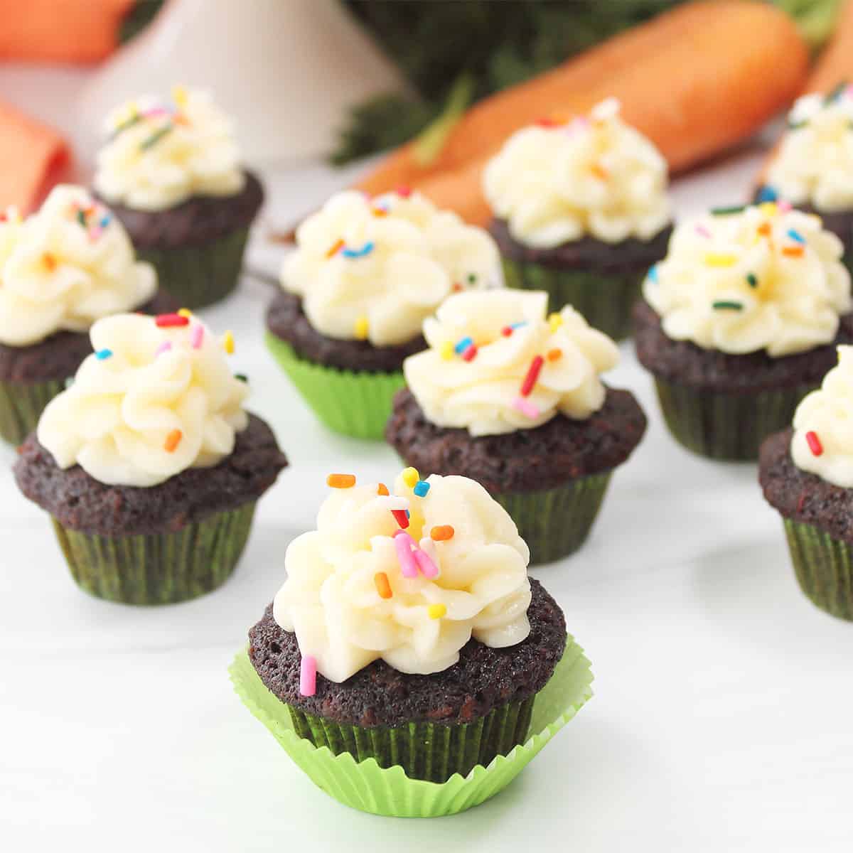 Mini chocolate carrot cake cupcakes scattered on table.