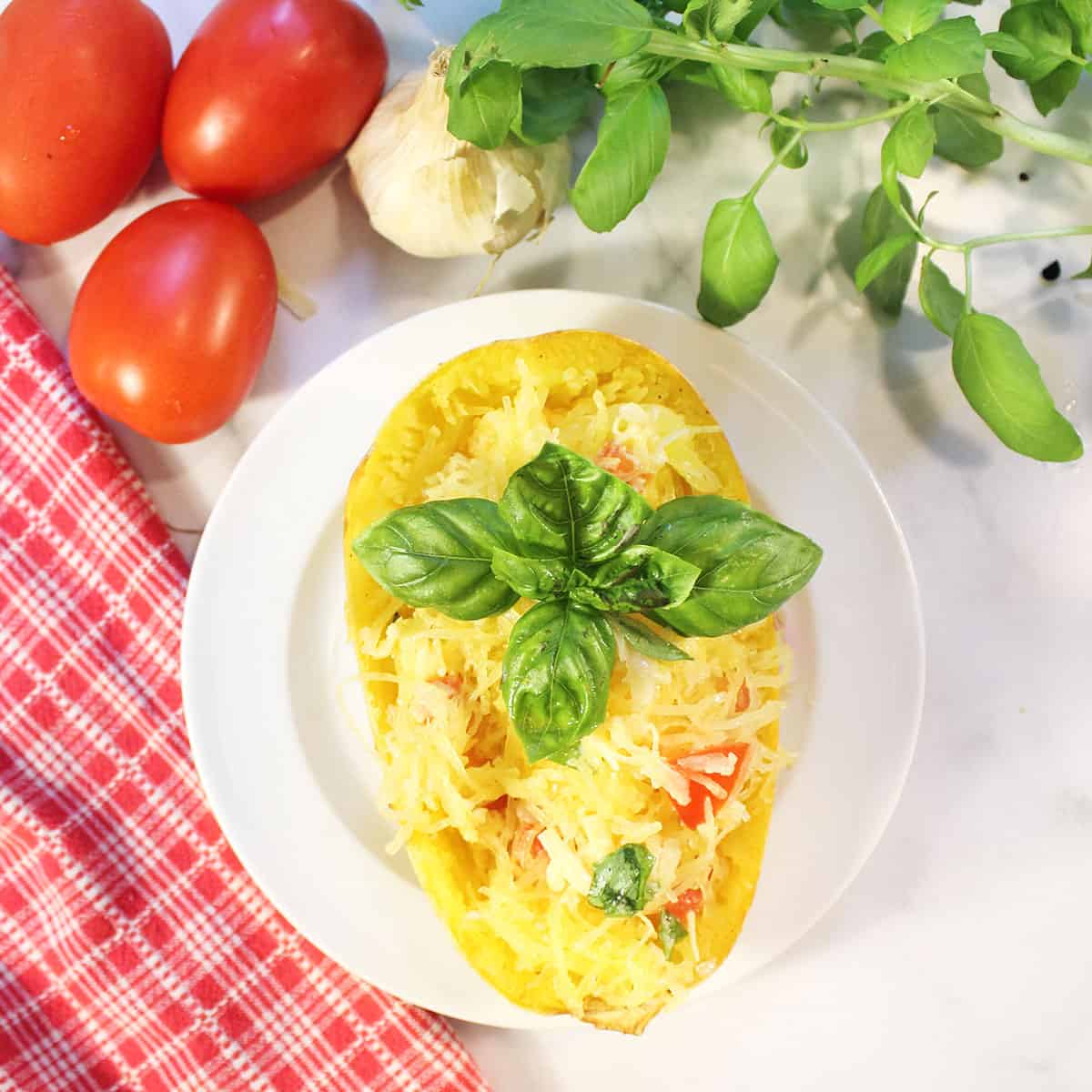 Overhead of stuffed spaghetti squash boat on white plate.