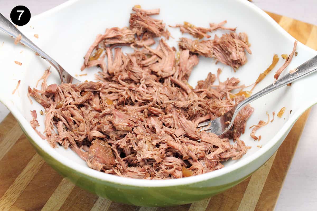 Shredding beef in large bowl for sandwiches.