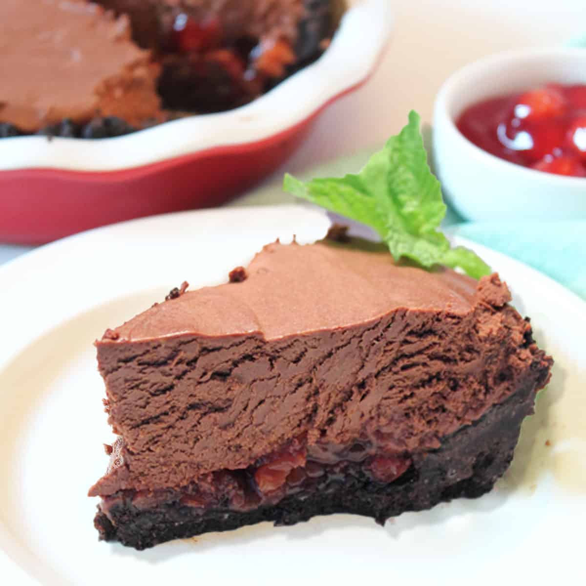 Slice of no bake chocolate tarton white plate with pie in background.