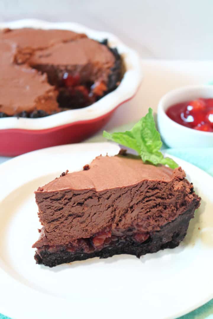 Slice of chocolate pie on white plate with pie in background.