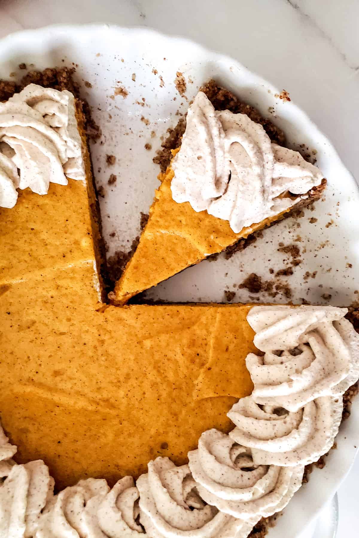 Overhead of pie showing piped whipped cream and slice cut.