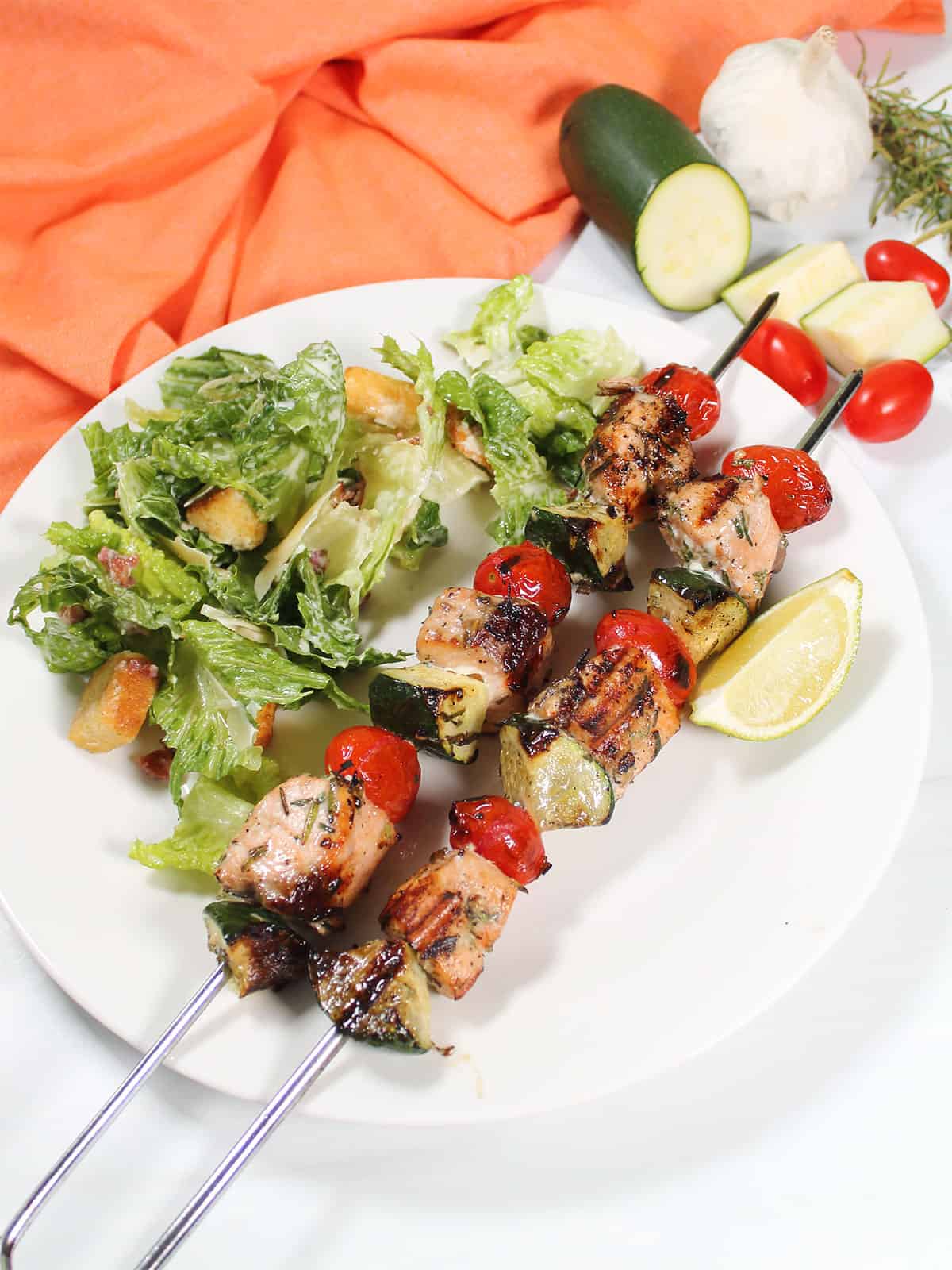 Plated salmon skewers dinner with side salad.