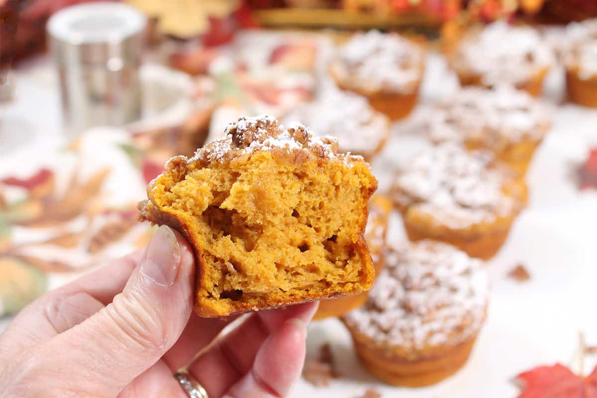 Holding streusel muffin with bite out of it.