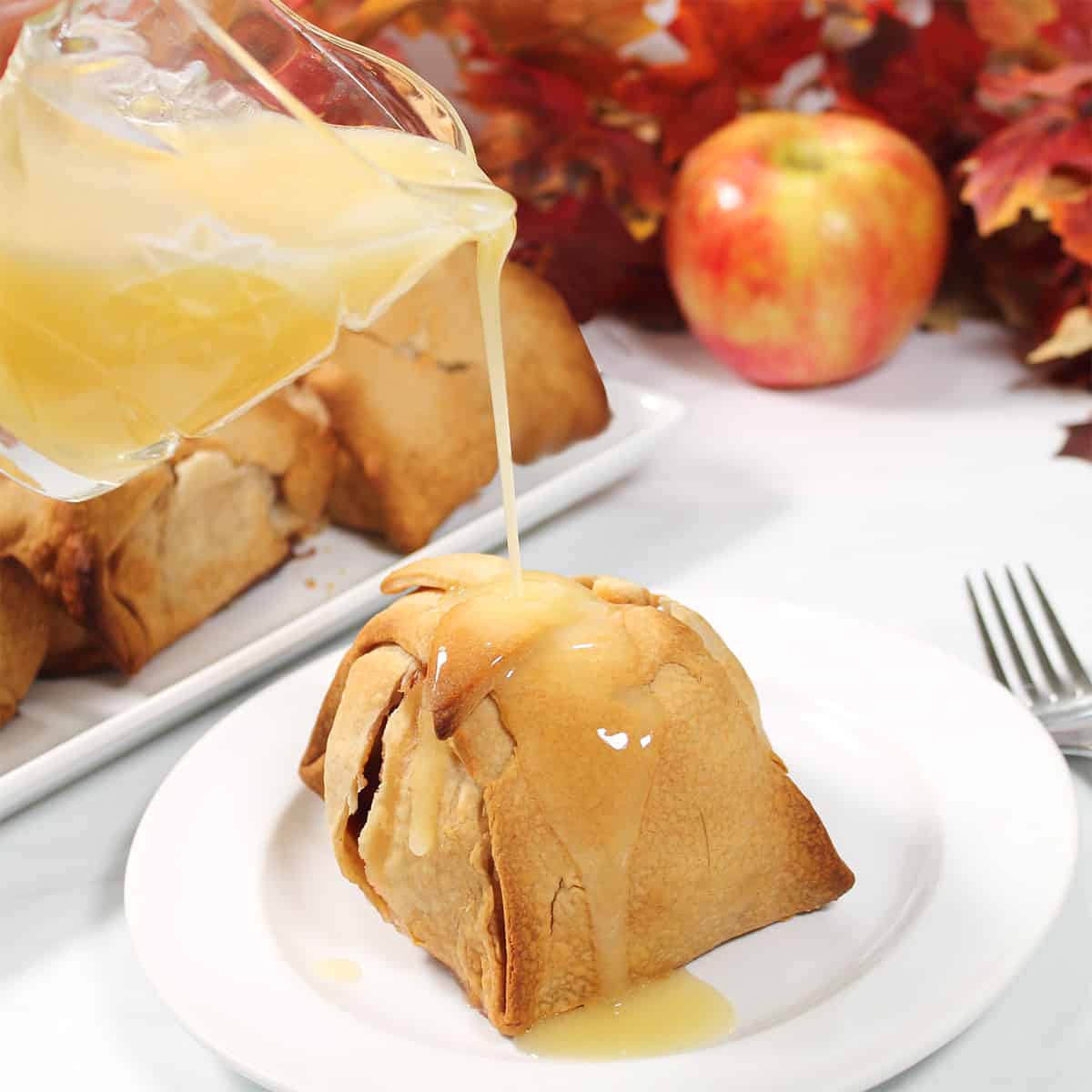 Pouring vanilla sauce over plated apple dumpling.