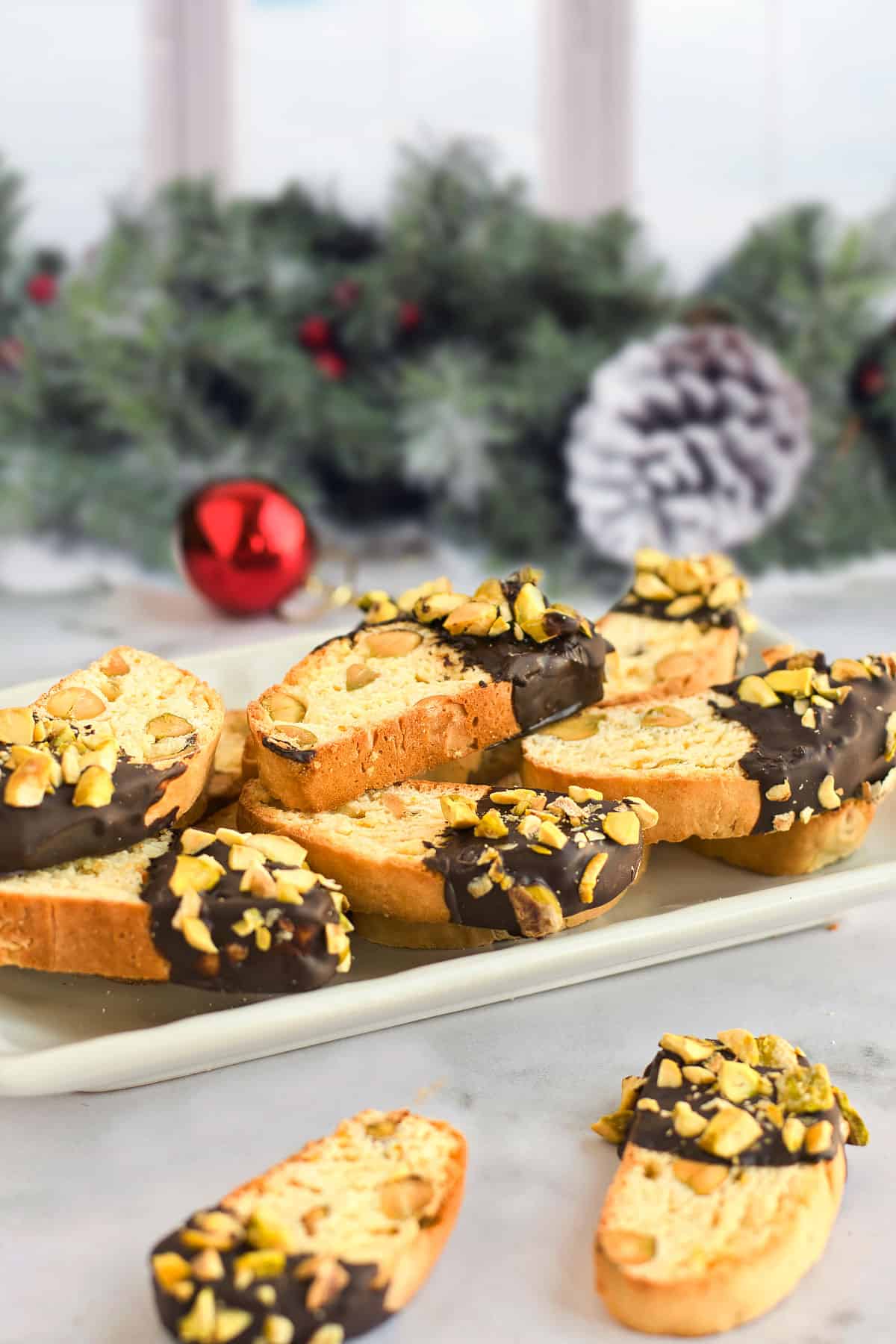 Biscotti on platter in front of greenery.