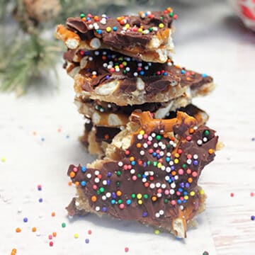 Chocolate Bark with pretzels stacked on white table.