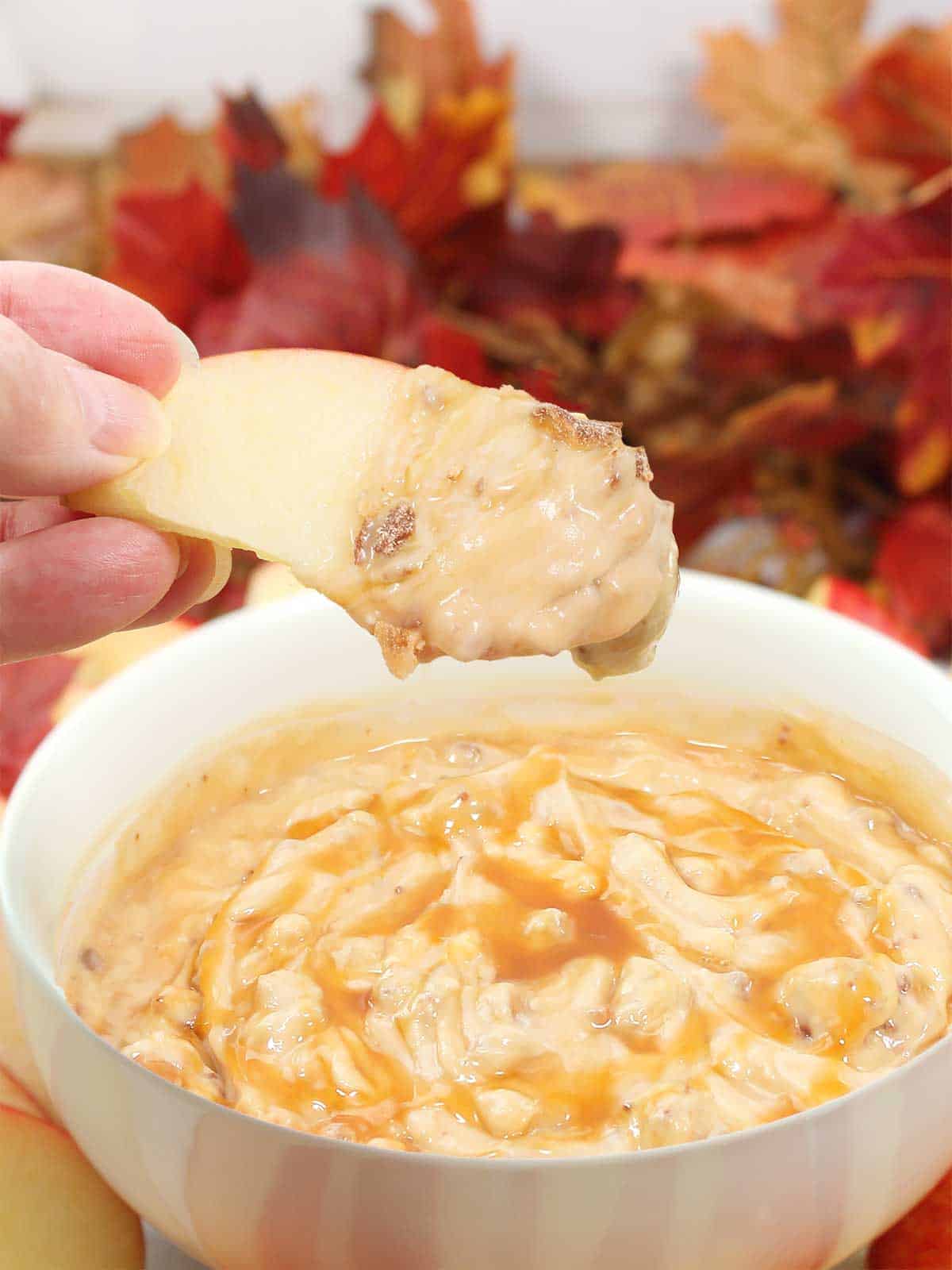 Holding apple slice with dip on it.