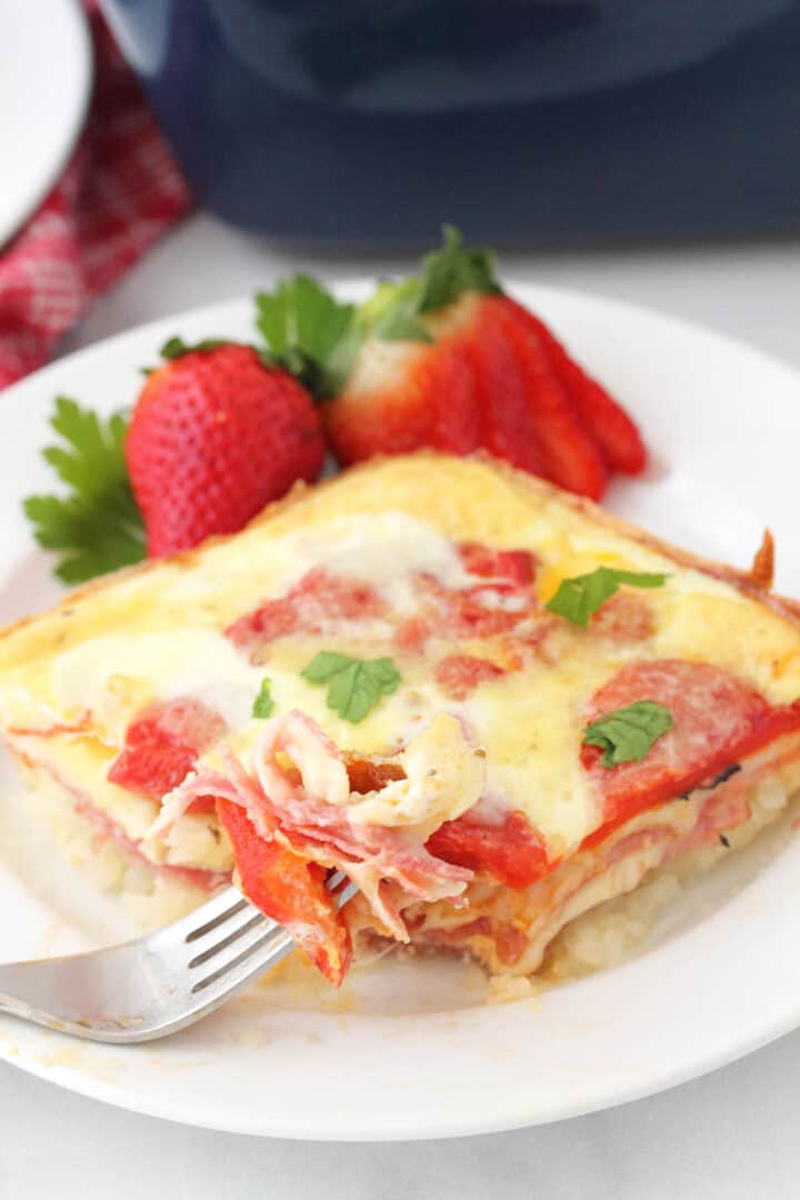 Italian Egg Bake on white plate with bite on fork and garnish of strawberries.