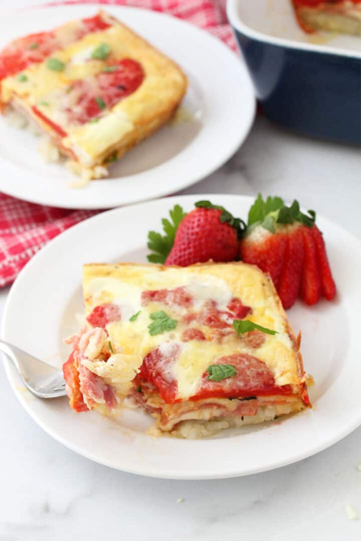 Two servings of Italian Egg Bake on white plates with casserole in background.