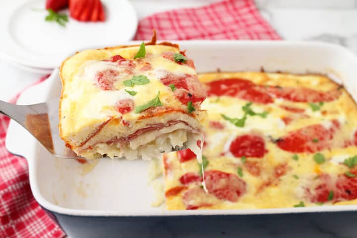 Lifting slice of breakfast casserole out of dish.