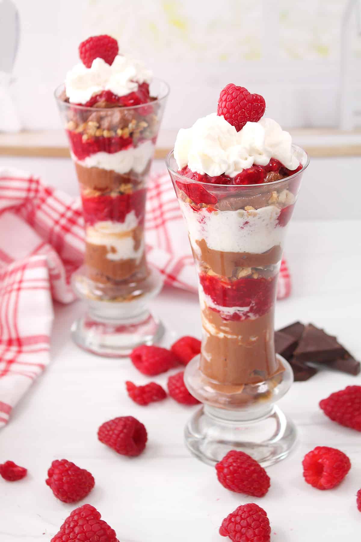 Two chocolate raspberry trifle desserts topped with whipped cream and raspberry.
