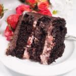 Closeup of slice of cake on white plate with roses.