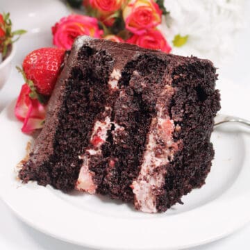 Closeup of slice of cake on white plate with roses.