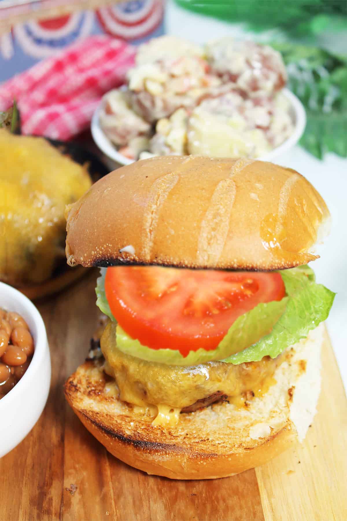 Dressed chorizo burger on bun with potato salad.
