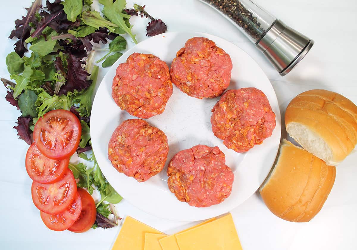 Formed burgers on white plate.