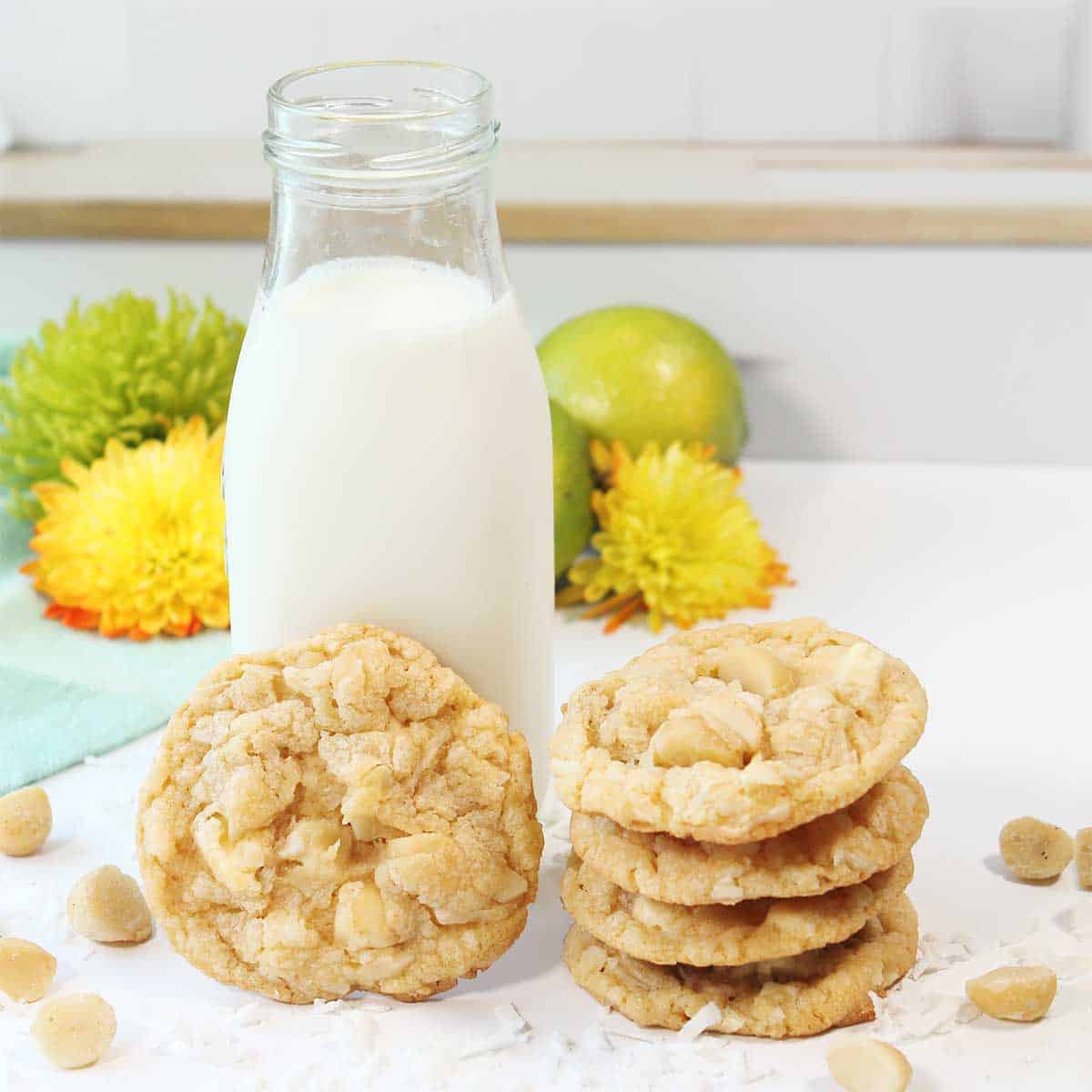 Key Lime White Chocolate cookies stacked and leaning on milk bottle.