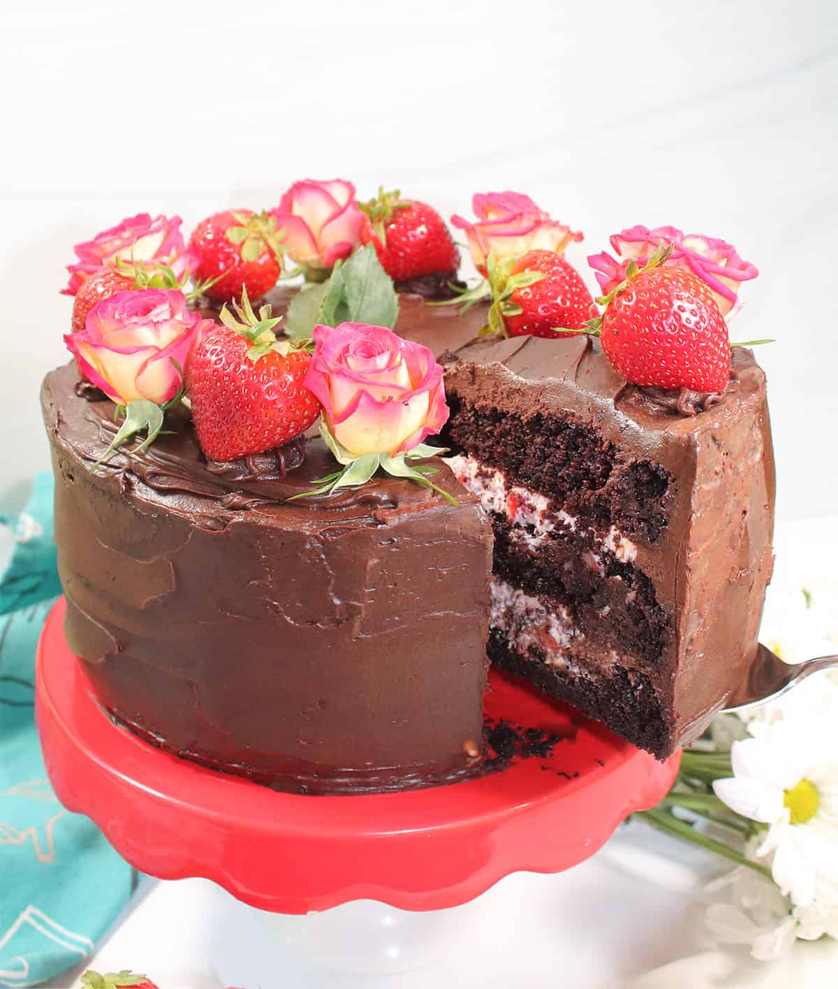 Lifting slice os cake with strawberry filling out of decorated cake.