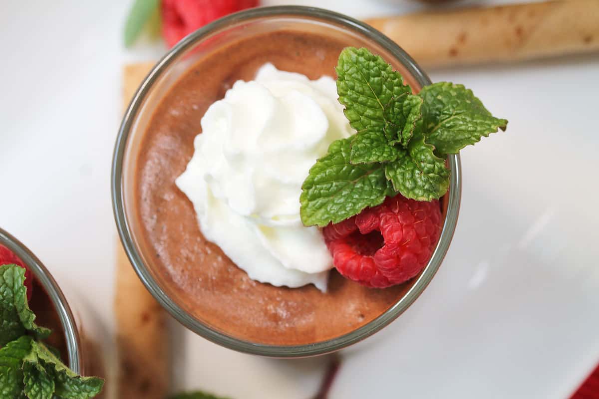 Overhead of single serving showing whipped cream, raspberry and mint sprig.