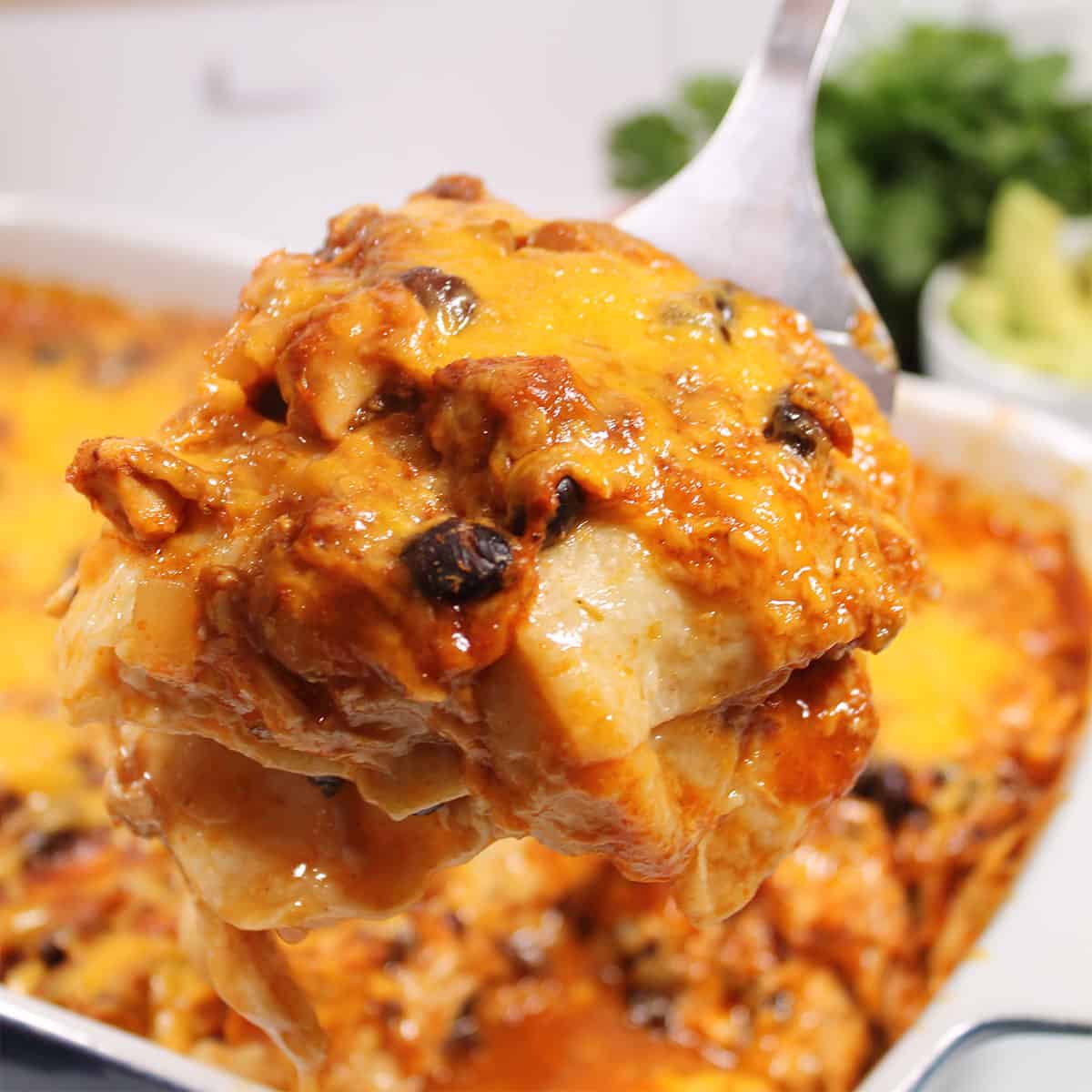 Lifting a serving of enchilada casserole on spatula.