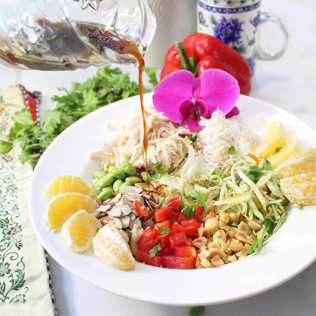 Adding dressing to noodle salad bowl.