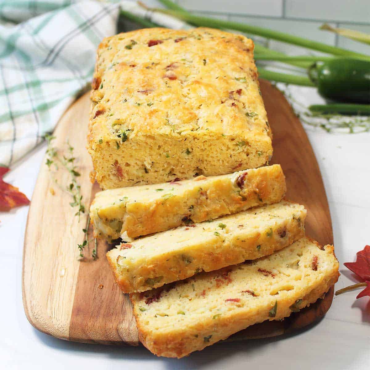 Cheddar bacon bread sliced on cutting board.