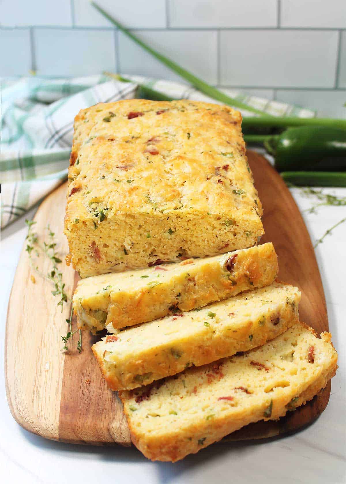 Bacon Bread on cutting board with three slices cut.