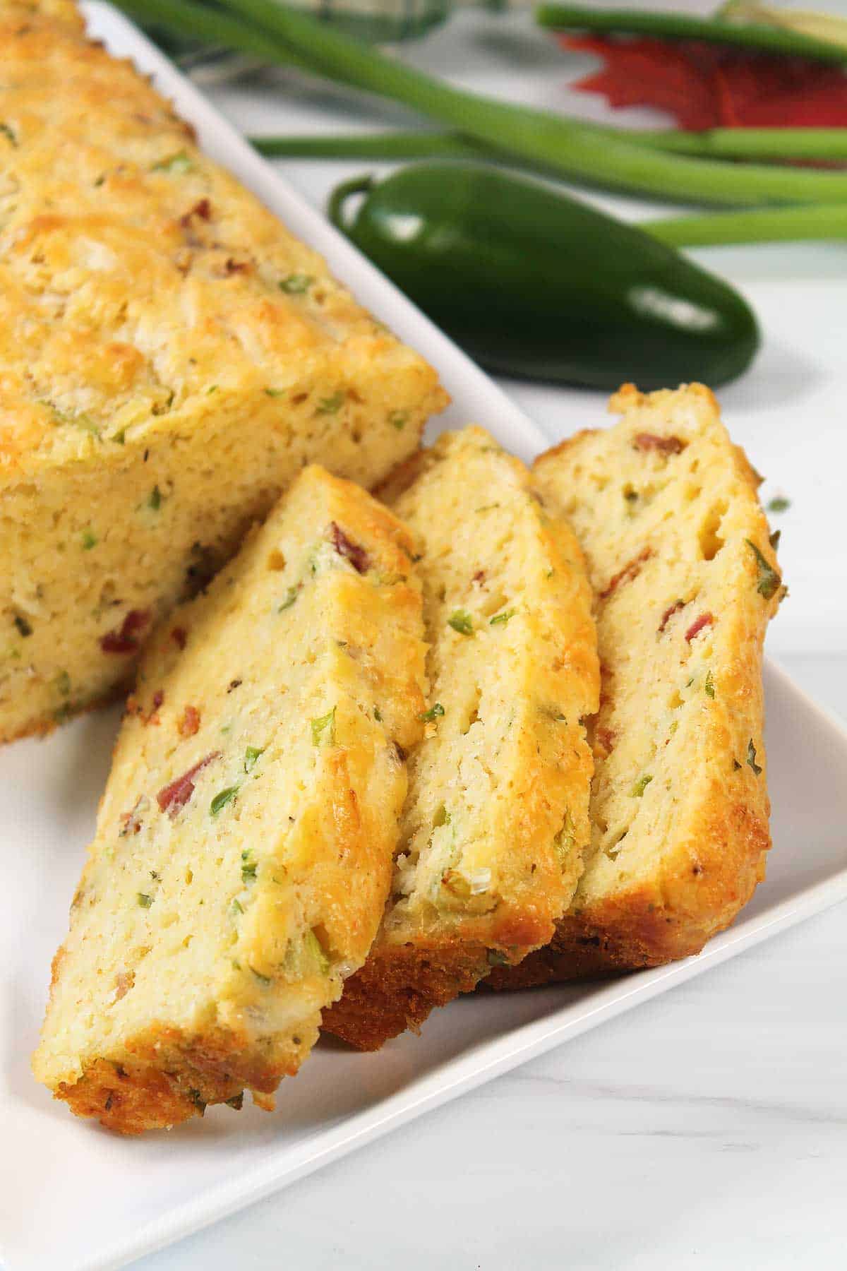 Closeup of three slices of bacon and cheese bread on white platter.