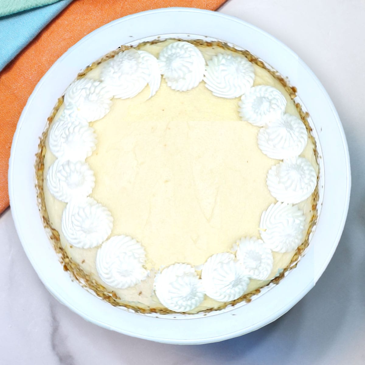 Frosted and piped cheesecake.