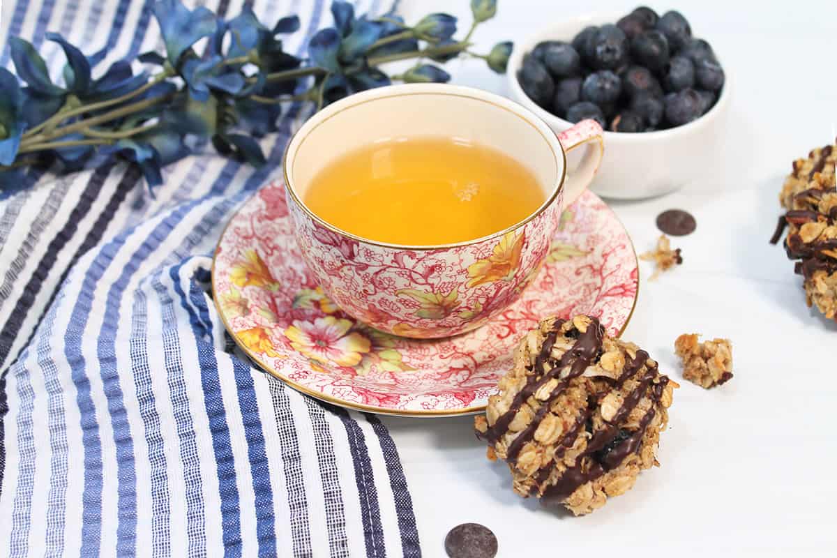 Breakfast cookie leaning against sauce of tea cup.