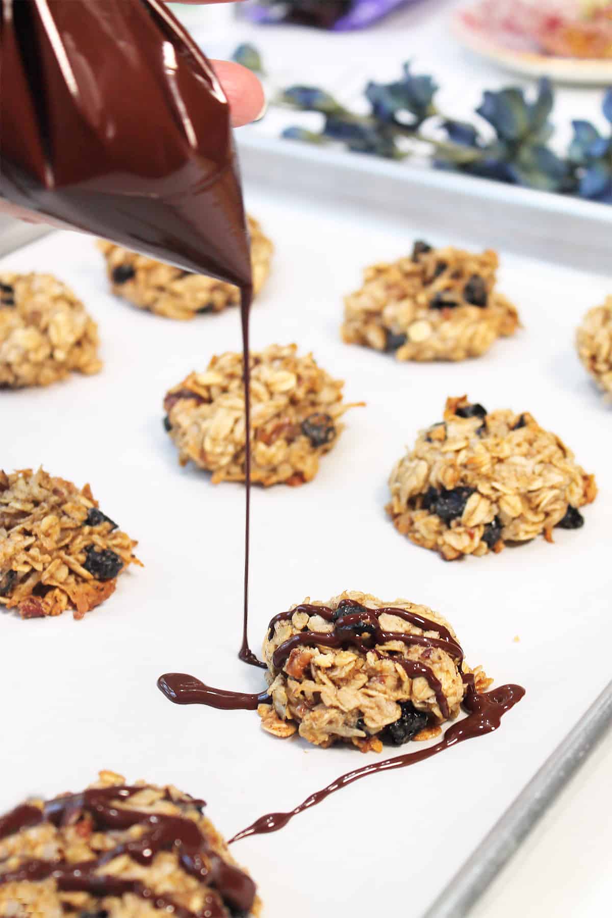 Drizzling baked cookies with chocolate.