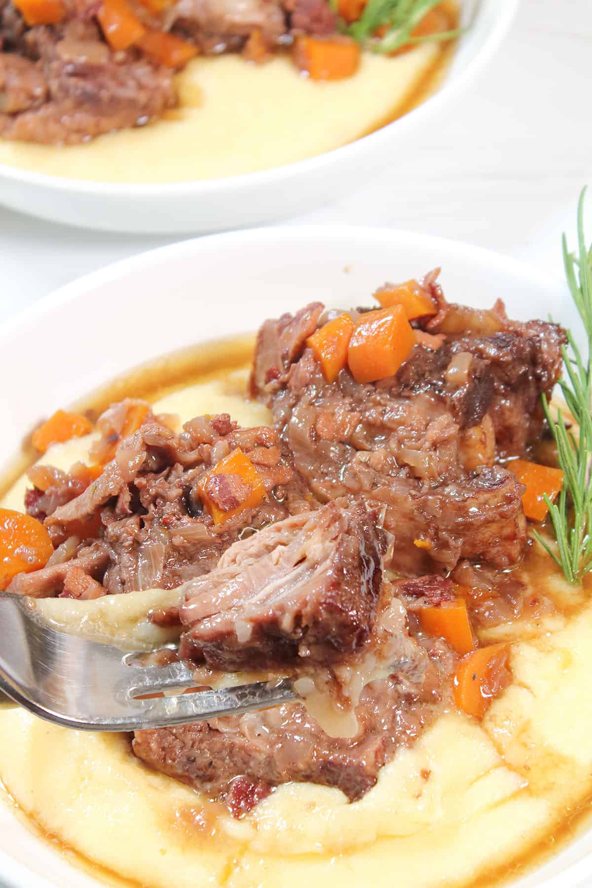 Bite of braised beef short ribs on fork.