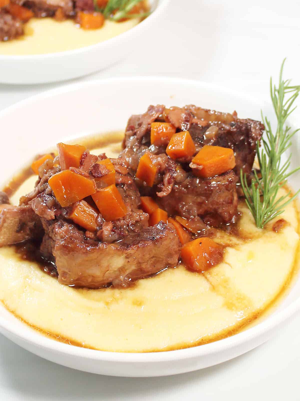 Plated dinner of Dutch Oven Braised Short Ribs over polenta.