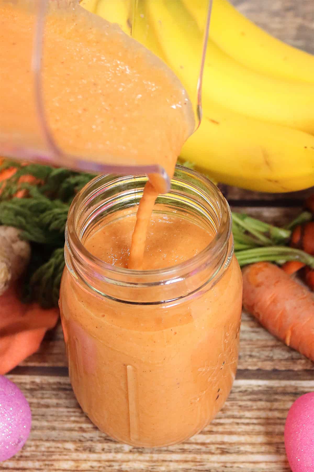 Pouring carrot banana smoothie into mason jar.