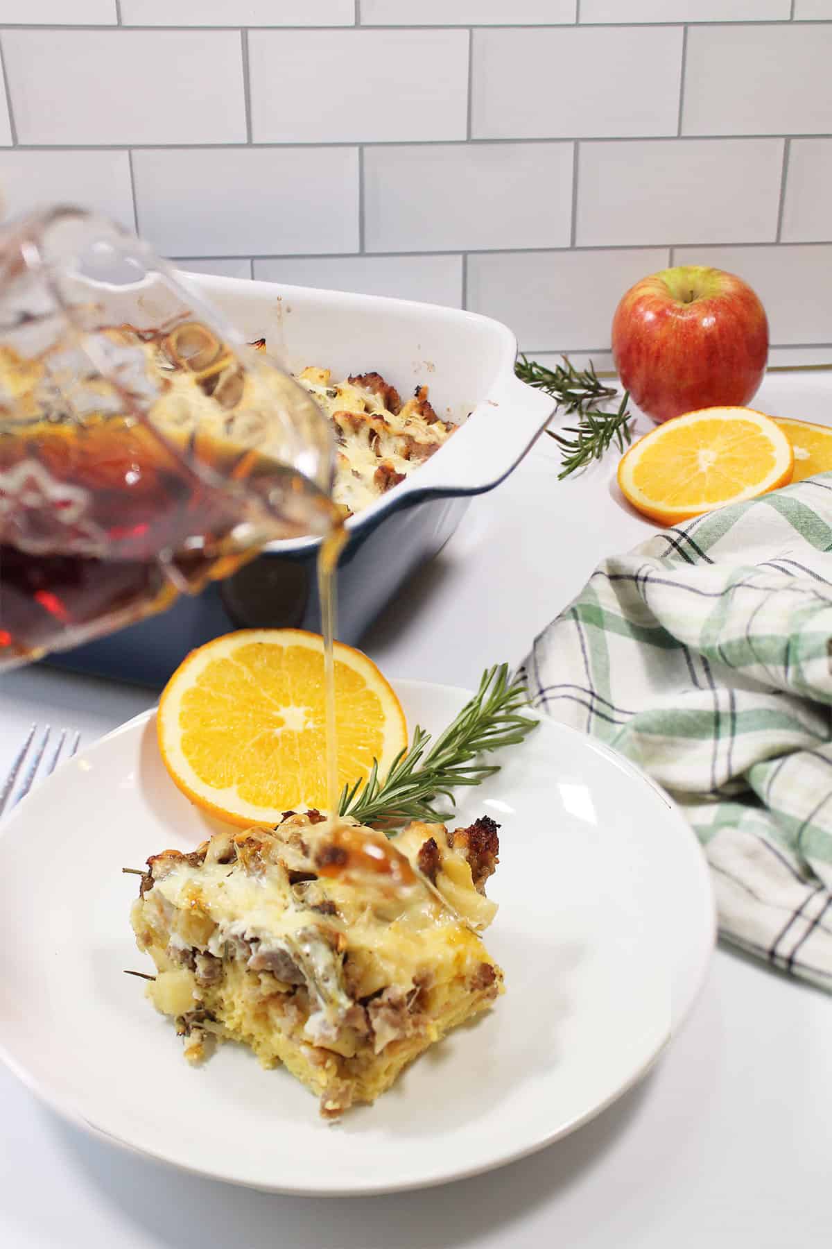 Pouring syrup on slice of breakfast casserole.
