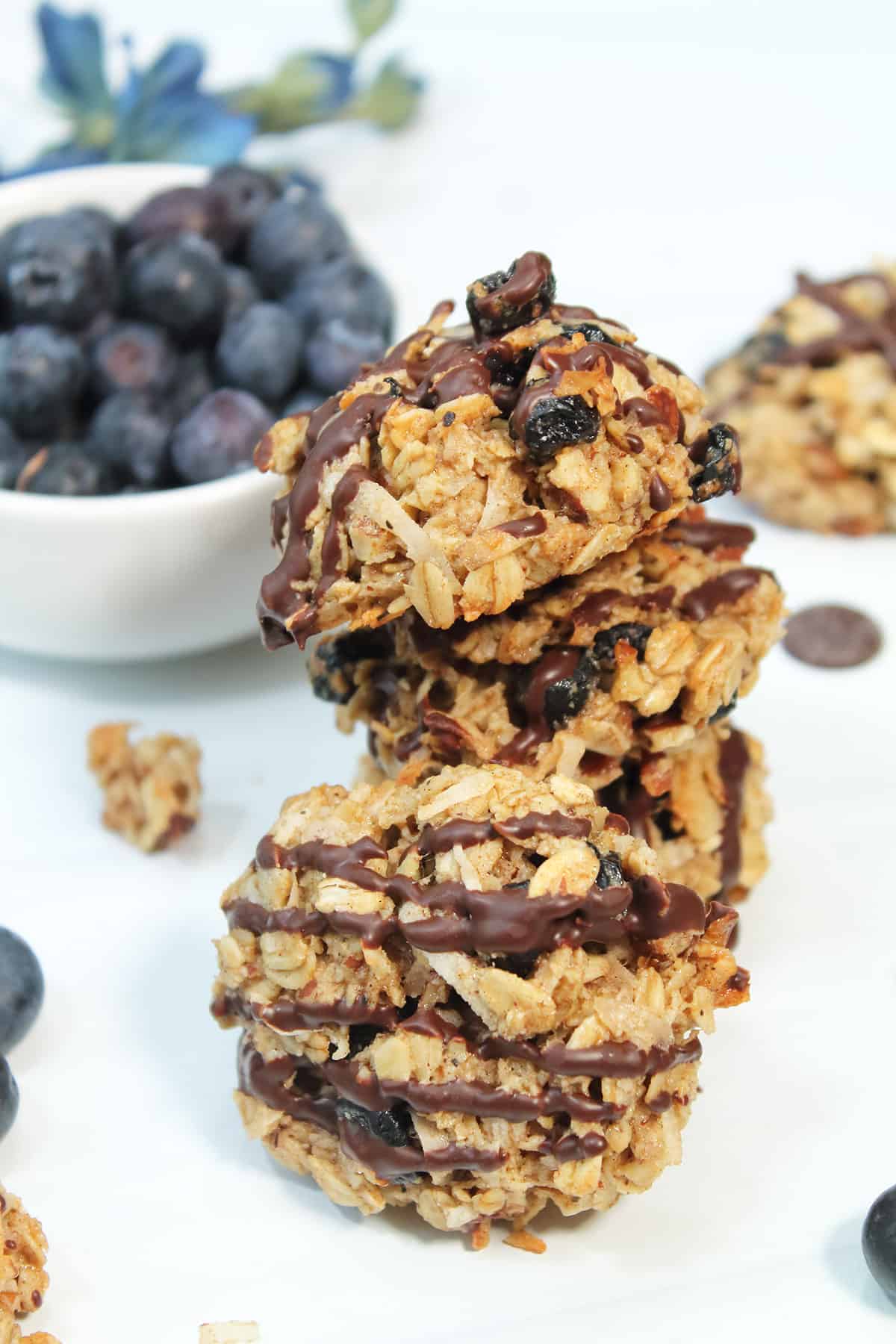 Stack of oatmeal cookies with bowl of blueberries.