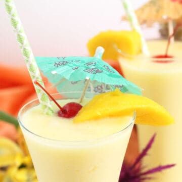 Closeup of top of glass filled with pina colada with mango.