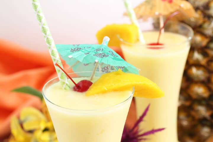 Closeup of top of glass showing garnish of mango slice, cherry and umbrella.
