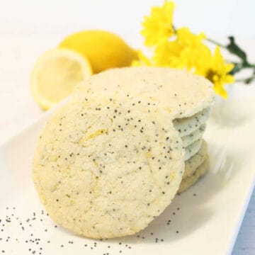 Cookies stacked on white platter with lemon in back.