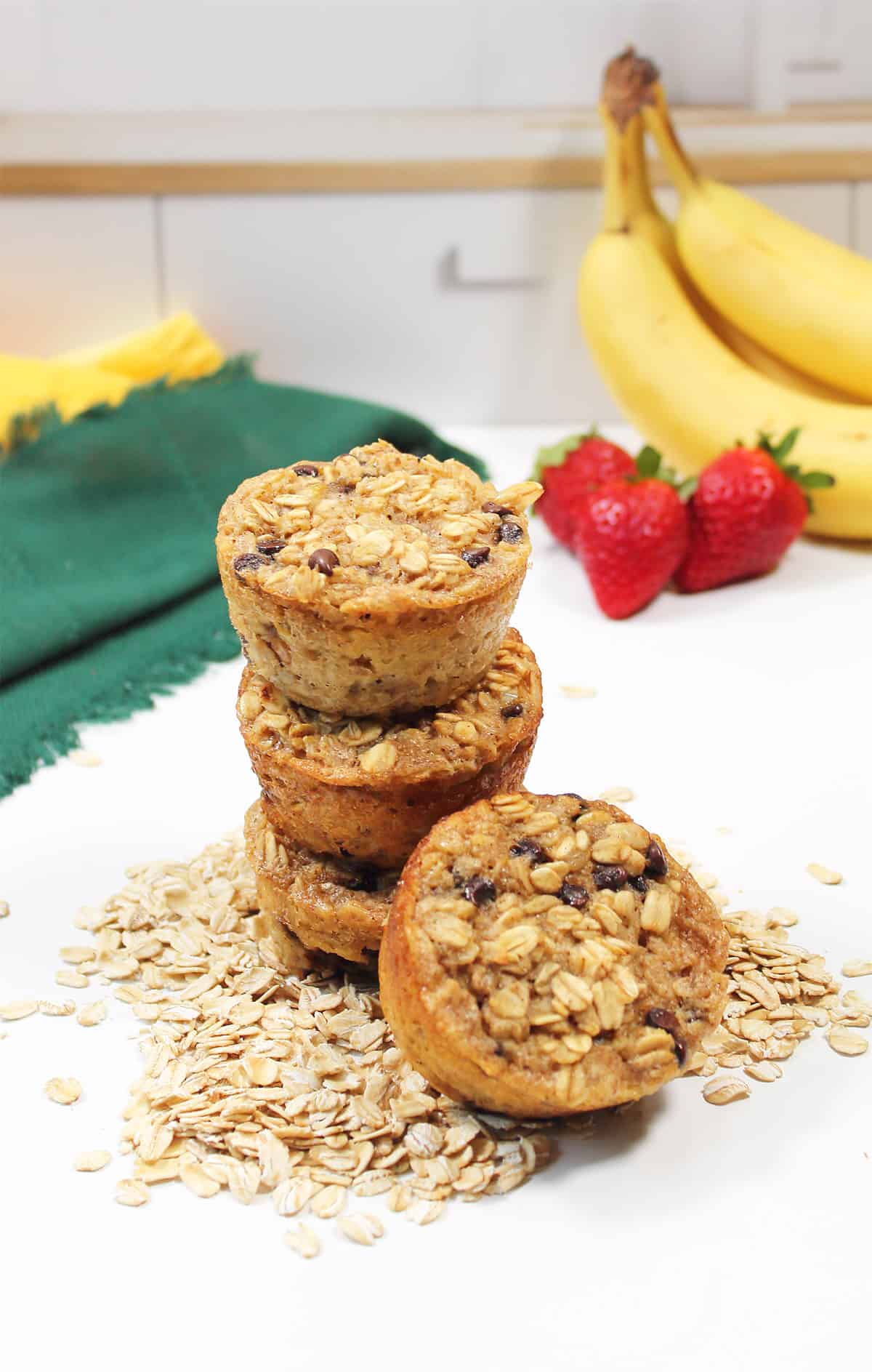 Stack of banana oatmeal chocolate chip muffins with scattered oats.