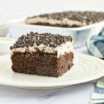 Chocolate poke cake slice on plate.