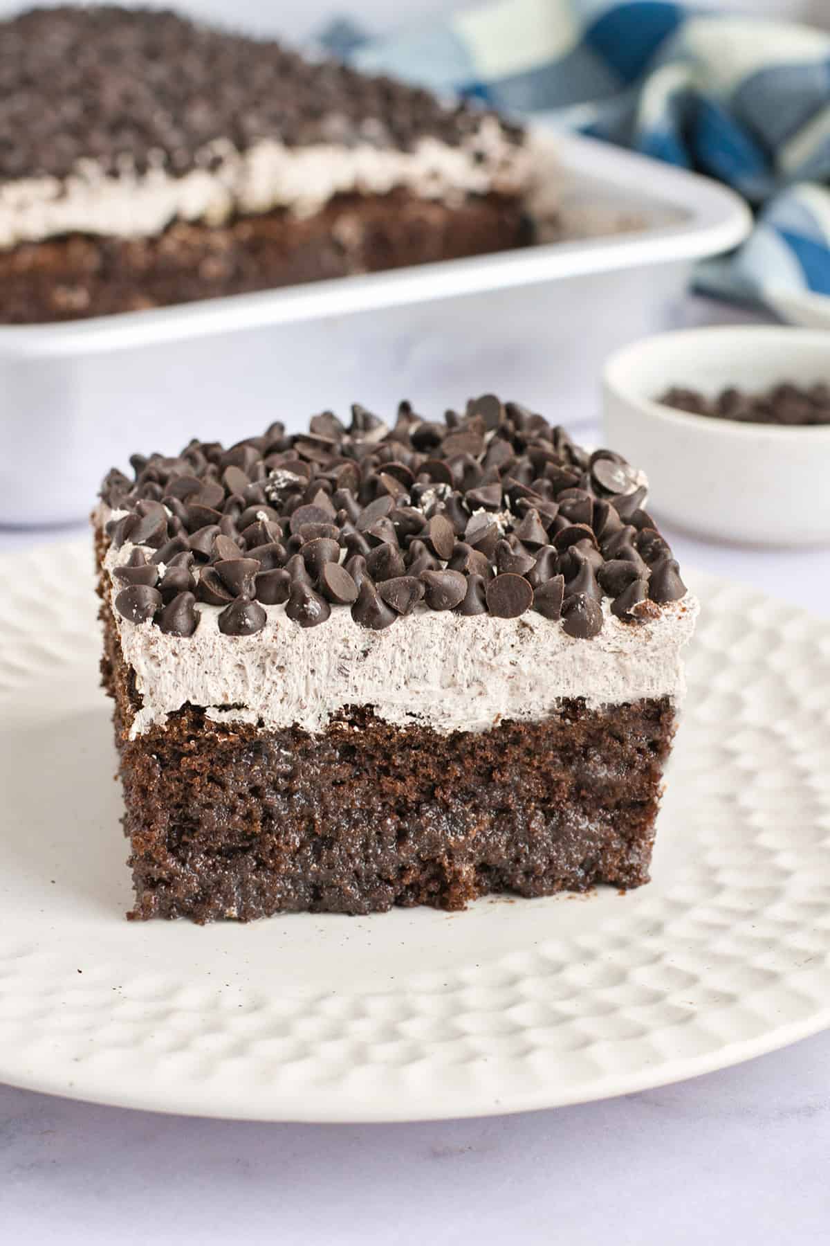 Slice of death by chocolate poke cake in front of baked cake.