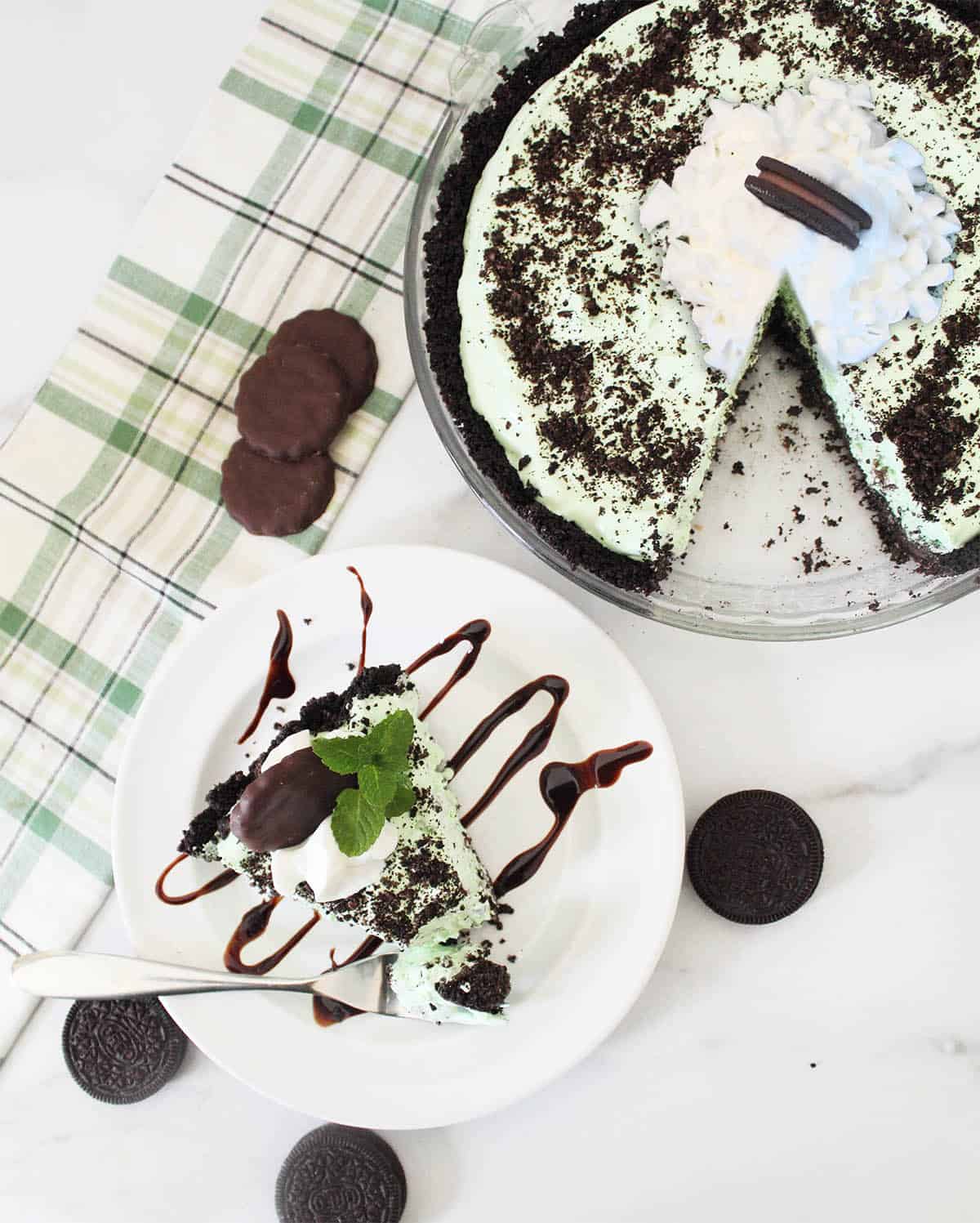 Overhead of slice of pie alongside decorated whole mint chocolate pie.