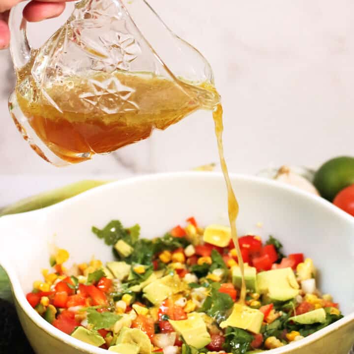 Pouring dressing over roasted corn salad.