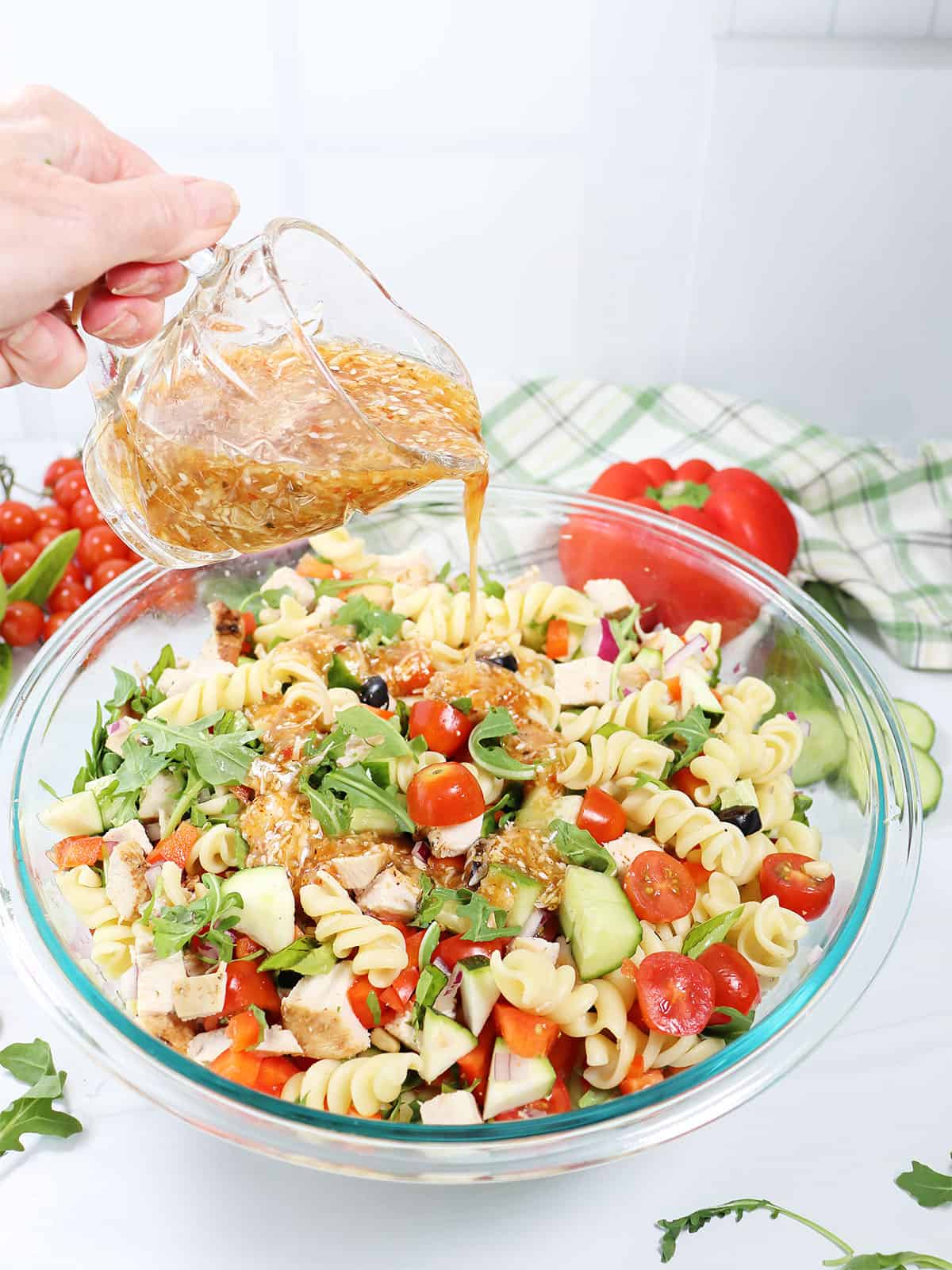 Pouring salad dressing on simple summer pasta salad.