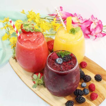 Three flavors of alcoholic slushies on wooden tray.